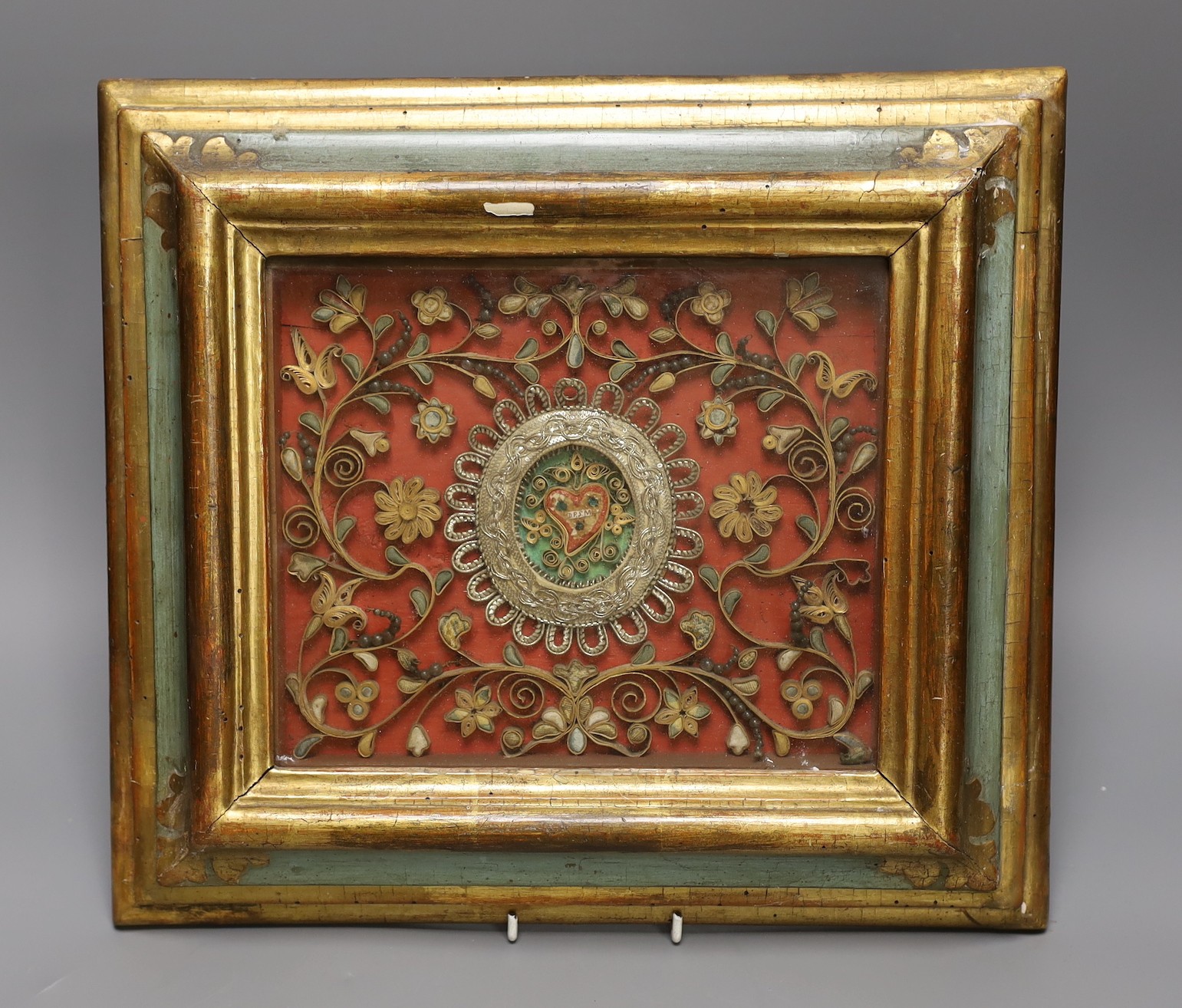 An 18th century century Italian scrolled paper and metal thread picture, in a polychrome and gilt frame, total size 34.5 cm x 38.5 cm